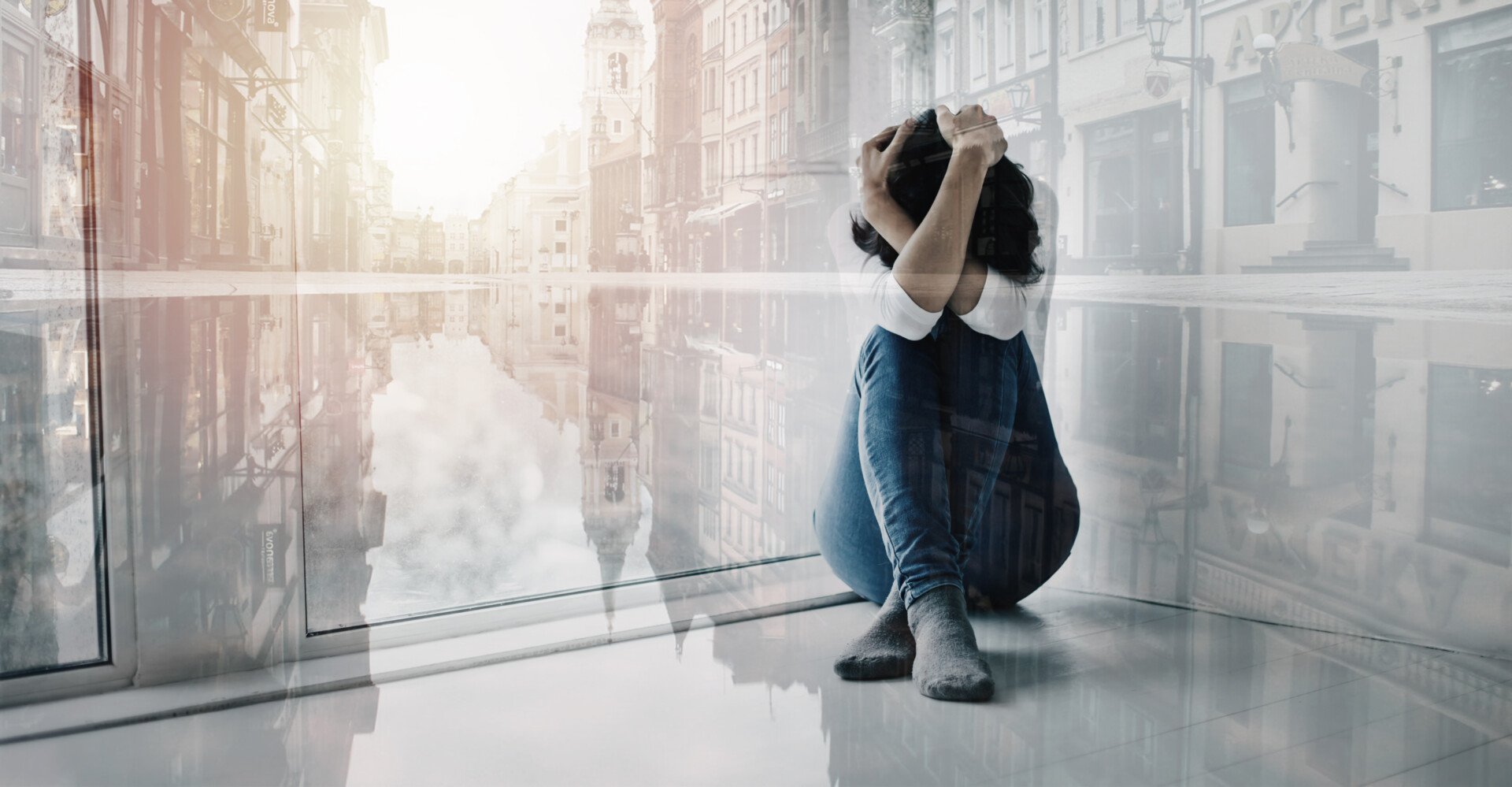 a woman sat on the floor with head in arms, looking distressed