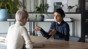 Multiracial businesswomen talk brainstorm at team meeting discuss business ideas together. Diverse multiethnic female colleagues or partners engaged in discussion. Interview concept