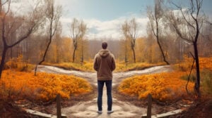 A young man stands at the crossroads of two roads in the autumn time.